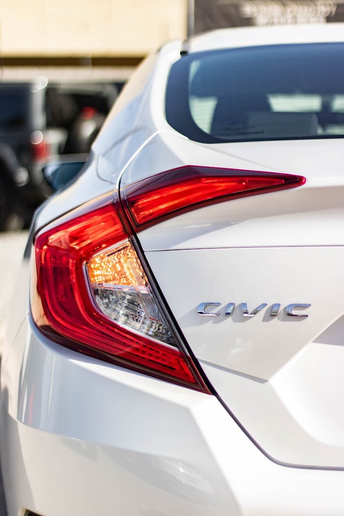 about-us Detailed shot of a white Honda Civic's tail light and logo in daylight.